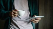 Tablet mit Nachrichtenseite neben einer Tasse Kaffee