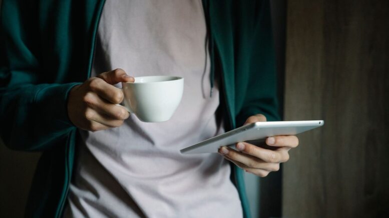 Tablet mit Nachrichtenseite neben einer Tasse Kaffee