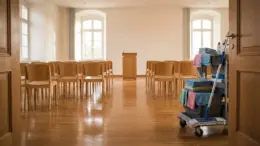 Gereinigter Seminarraum einer Stiftung mit Stuhlreihen und Reinigungswagen im Morgenlicht